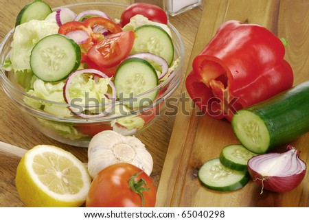 Vegetable salad bowl and salad ingredients on kitchen table