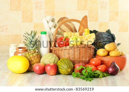 Groceries in wicker basket consisting of vegetables, fruits, dairy and bakery products on kitchen table
