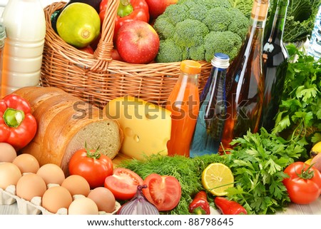 Groceries in wicker basket including vegetables, fruits, bakery and dairy products and wine