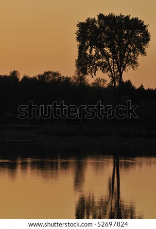The last light of the day creates an orange backdrop to a silhouetted shoreline.