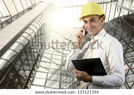 Young architect wearing a protective helmet standing on the building outdoor background