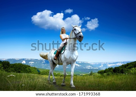 Young horsewoman riding on white horse, outdoors view