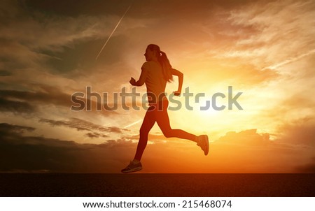 Beautiful silhouette of female running on road under sky with sun light