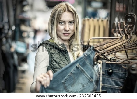 Beautiful blonde female looking jeans in the boutique