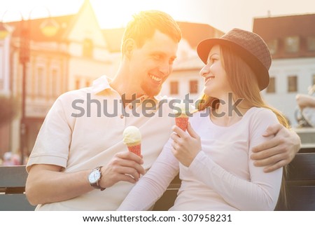 Happiness couple with ice cream sitting at street under sunlight