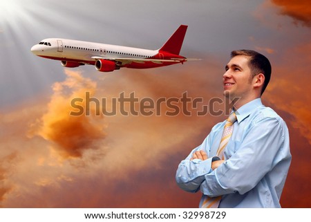man looks at airplane in air with sunrise sky