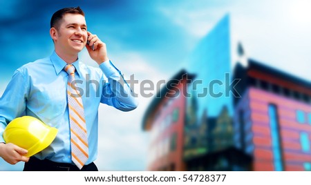 Young architect wearing a protective helmet standing on the building background