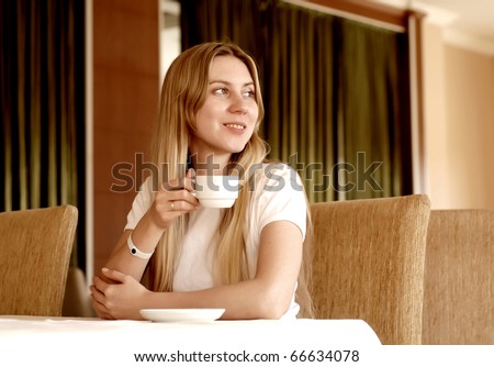 Happy woman in white with cup of coffee or tea.