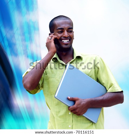 Young happy black man or student with laptop on the business background