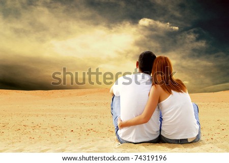 Young couple seating in desert in sunny day
