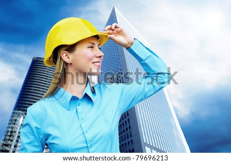 Young architect-woman wearing a protective helmet standing on the building background