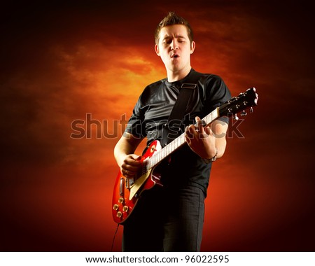 Rock guitarist play on the electric guitar around fire flames