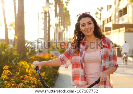 Smiling beauty with her bike - Smiling young woman holding bike handlebars with sunglasses on her head