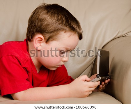 Couch potato concept of boy playing video game while resting on sofa