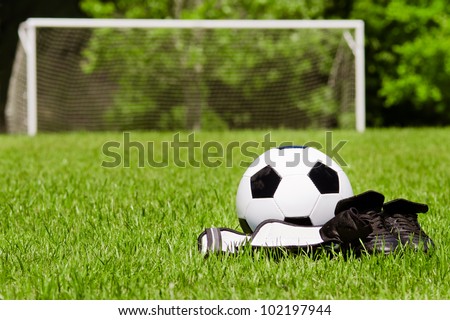 Child sports concept with soccer ball, cleats, shin guards on field