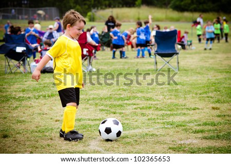 Young child boy playing soccer during organized league game