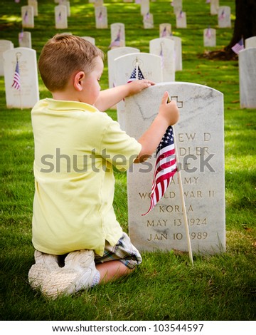 MARIETTA, GA - MAY 26: An unidentified boy straightens a flag on a veteran\'s grave on May 26, 2012, for Memorial Day Weekend at the National Cemetery in Marietta, Ga.