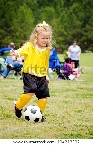 Cute young girl in uniform playing in organized youth league soccer game