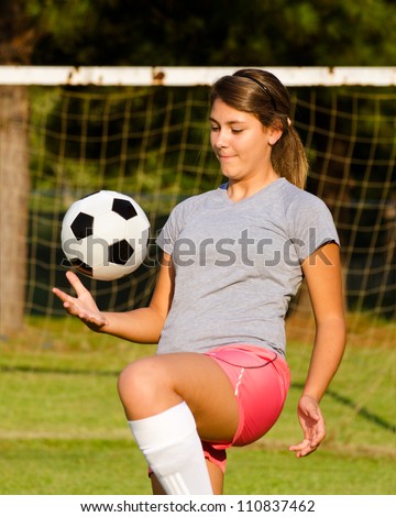 Teen girl juggling soccer ball with her knees