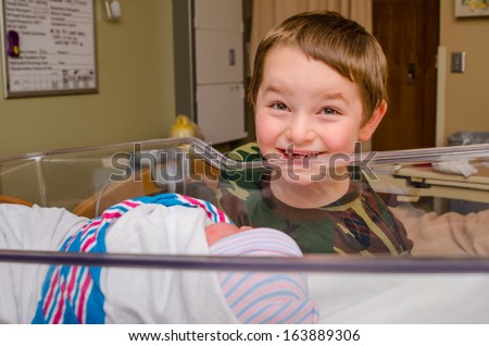 Excited boy meets his infant sibling for the first time after delivery at hospital