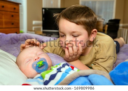 Child comforting his baby brother while he\'s sleeping in candid family moment