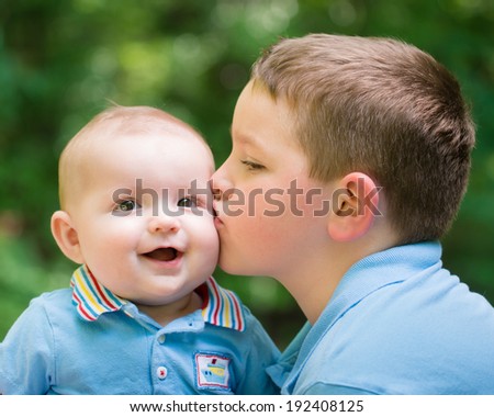 Happy baby boy kissed by his older brother