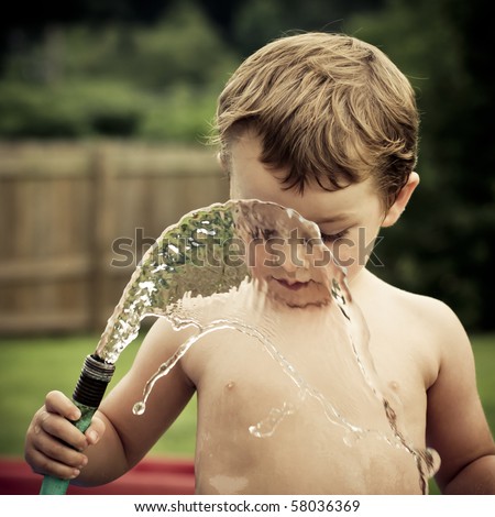 Child, Boy or kid plays with water hose outdoors during summer or spring to cool off in hot weather
