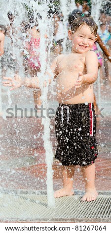 Happy young boy or kid has fun playing in water fountains at Centennial Olympic Park in Atlanta, Georgia, on hot day during summer.