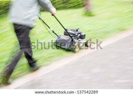man garden worker cutting overgrown grass with lawn mower weeding machine blur motion