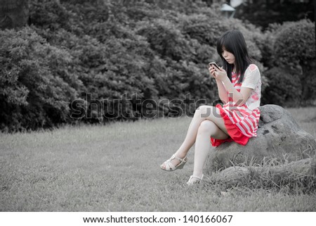 Beautiful Asian woman using cell phone outdoor
