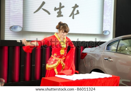 GUANGZHOU, CHINA - OCT 02:An unidentified dancer dance and paint traditional Chinese wash painting with Qilin car model at Baiyun international automobile exhibition on Oct 2, 2011 in Guangzhou China.