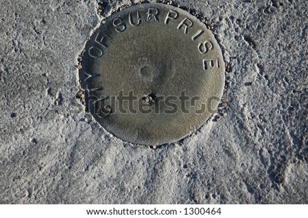 Image of brass property survey marker embedded in concrete along public street in city of Surprise, Arizona.
