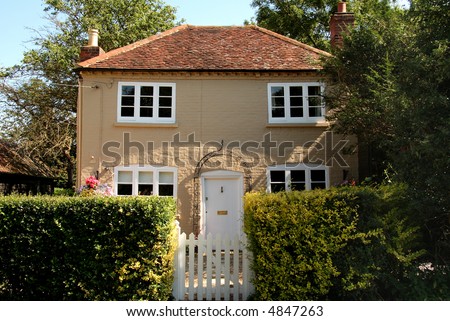 Quaint Cottage in Rural England with gate and neatly trimmed Hedge to the front