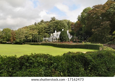English Country House and garden with hedge and meadow in front