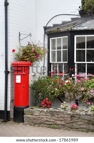 Red English Post Box outside a flower strewn English Village Post Office
