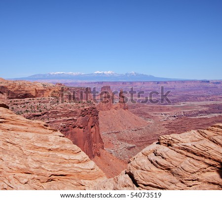 Red Rocks and boulders in Canyon Land Utah in the USA with snow capped mountains in the far distance