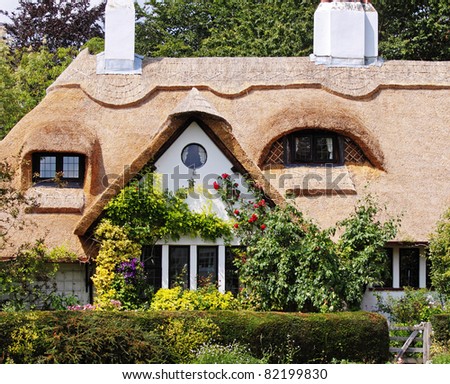 Traditional Thatched English Village Cottage and garden with climbing Roses