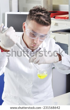 Attractive young PhD student scientist observing the yellow indicator color shift after the solution destillation in chemical laboratory
