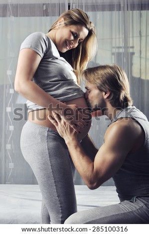 Happy future daddy kissing his unborn baby boy