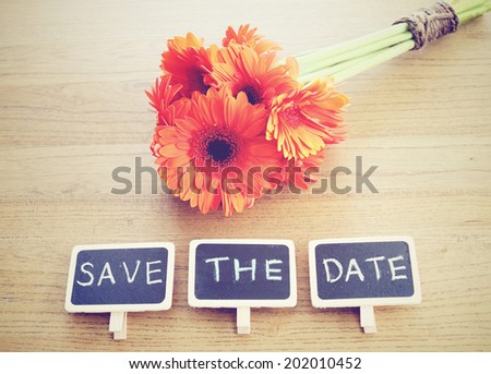 Save the date written on blackboard with flower, nostalgic still life, retro instagram filter effect