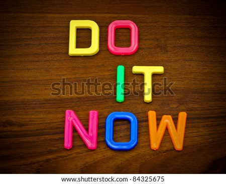 Do it now in colorful toy letters on wood background