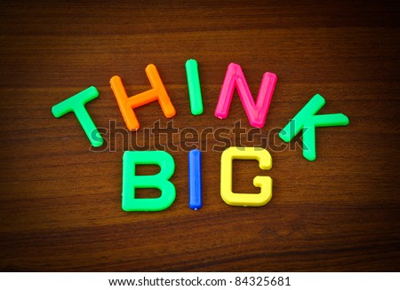Think big in colorful toy letters on wood background