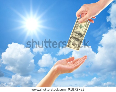 Hand giving money to other hand over clouds and sun
