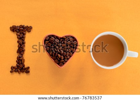 Heart shape made from coffee beans with a  cup of coffee, spelling I love coffee