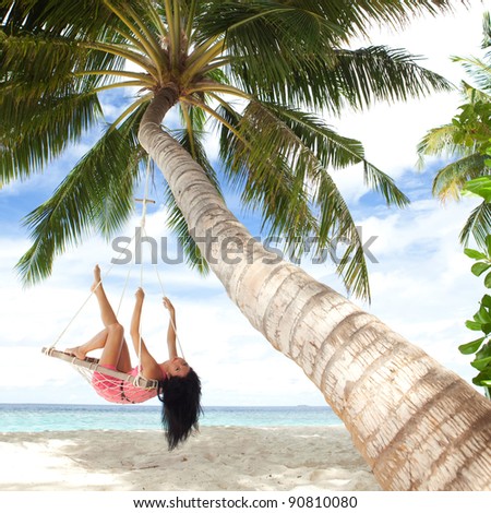 Happy woman relaxing in hammock on a tropical beach