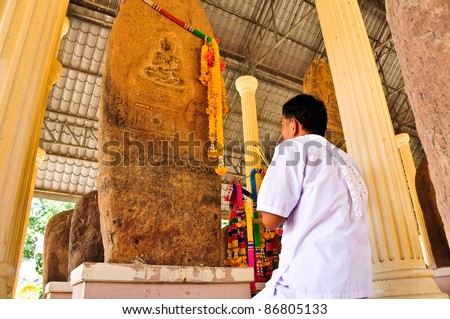 The old man worship the boundary marker of a temple with a stone plate