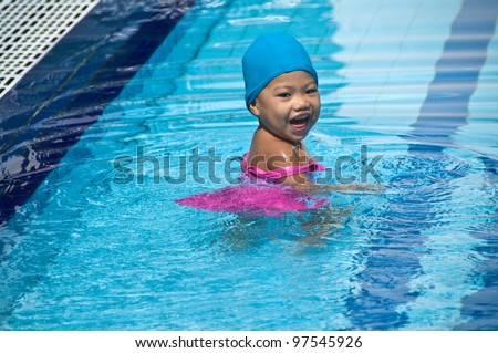Happy little asia girl learning to swim in the pool.