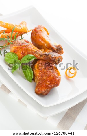 Delicious grilled chicken legs on white plate with fresh herbs and carrots isolated on white background. Culinary poultry eating.