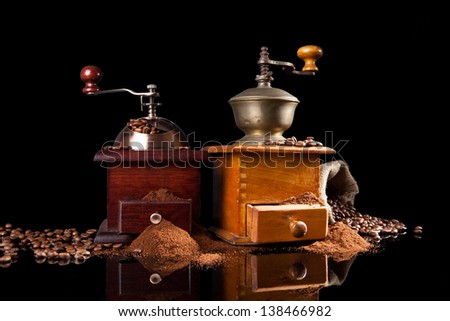 Freshly roasted coffee with aroma, old vintage wooden coffee mill, sack with coffee beans on black background. Aromatic luxurious coffee background.