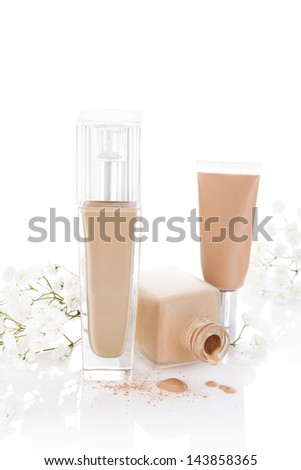 Beige liquid foundation and make up isolated on white background with clipping path and white flower. Luxurious feminine cosmetics.